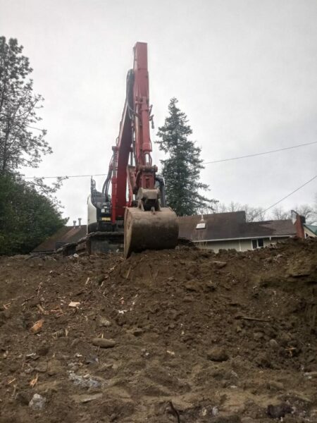 Red crane excavating dirt at construction site