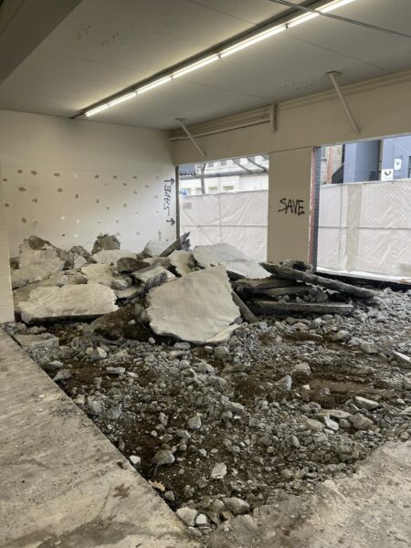 Interior demolition site with rubble and 'SAVE' graffiti