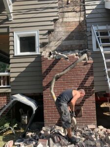 Worker removing debris from damaged brick chimney