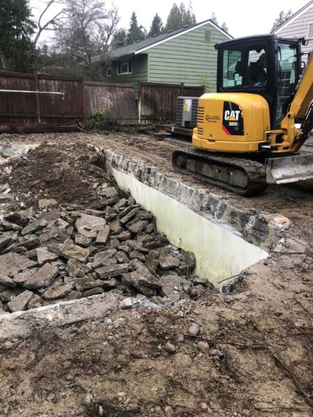 Mini excavator at residential retaining wall construction site