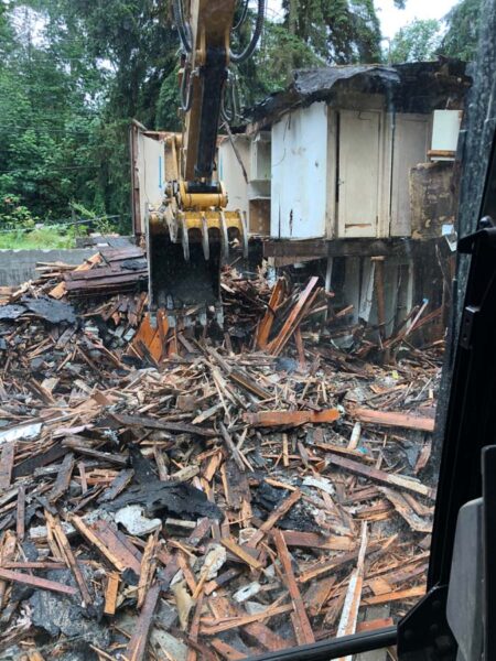 Excavator demolishing old wooden house