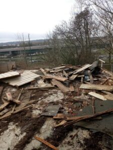 Pile of construction debris near trees and a building