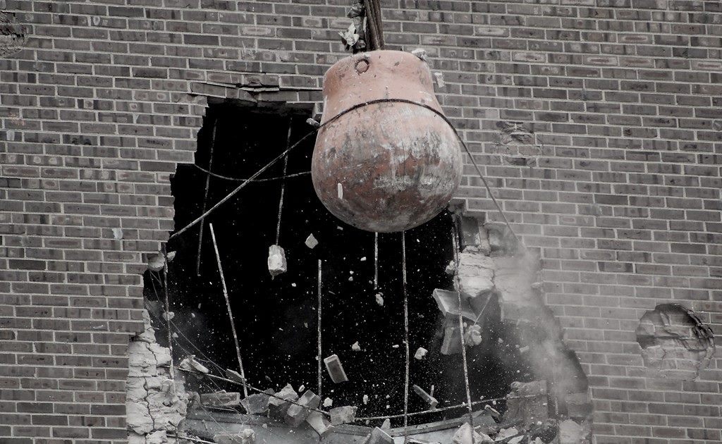 Wrecking ball breaking through a brick wall