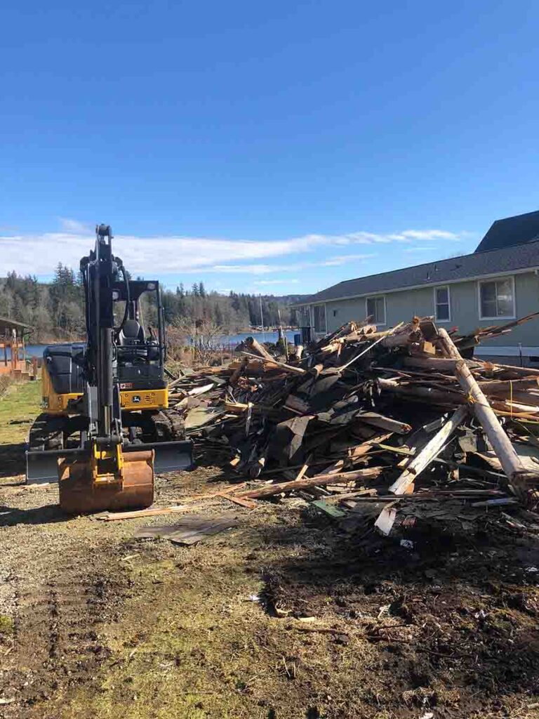 Excavator clearing large pile of wood debris