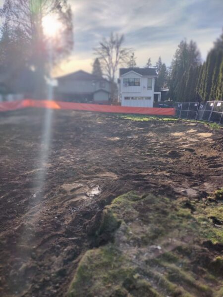 Muddy construction site with sun flare and house