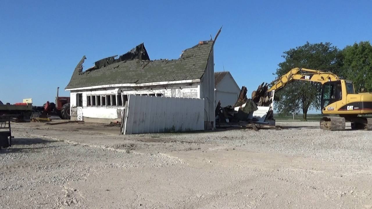 Excavator demolishing old white house