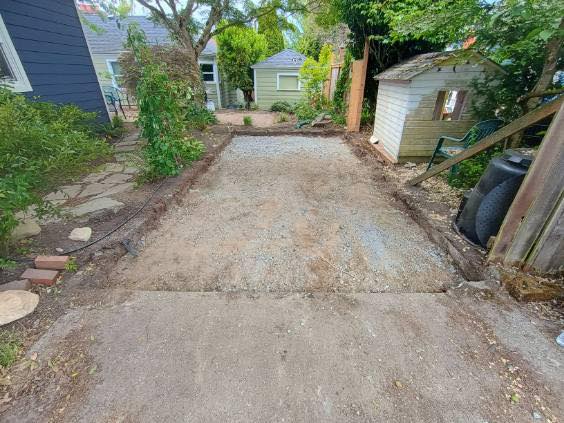 Gravel driveway between small houses and greenery