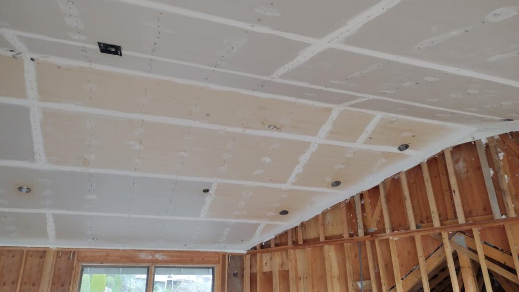 Unfinished ceiling and exposed wall studs in room.