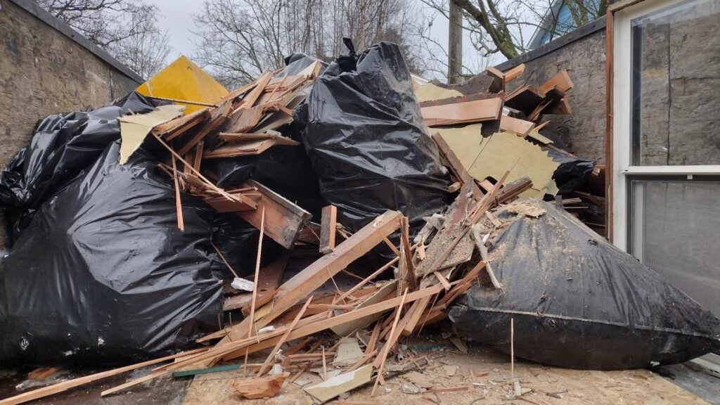 Pile of construction debris and trash bags outdoors